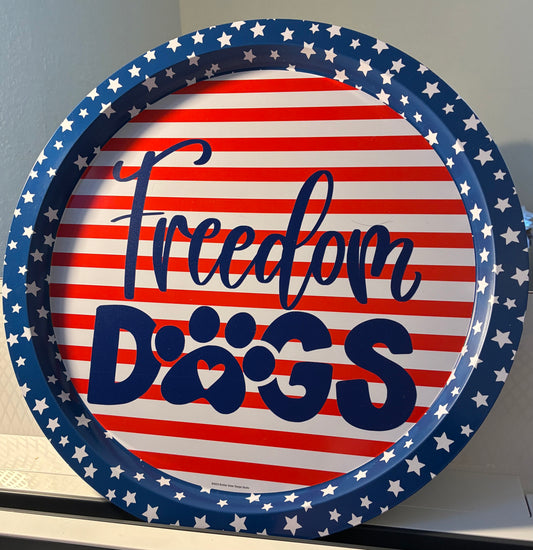 Round patriotic platter with red and white stripes, a blue star border, and the phrase “Freedom Dogs” in bold blue letters. The word “Dogs” features a paw print with a heart shape in the center.